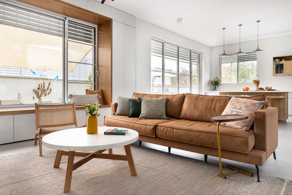 עיצוב קיר טלוויזיה מודרני הכולל מזנון צף בנגרות אישית, שילוב של קיר נגרות לבן ופינת ישיבה מובנית על החלון בסגנון מינימליסטי